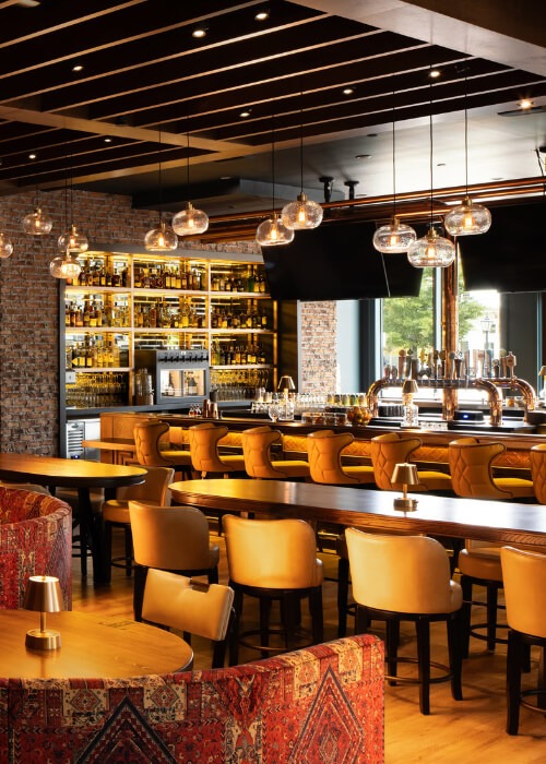 Stylish bar interior with warm lighting, wooden furniture and stocked bar